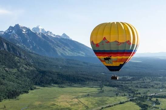 Hot air balloon floating above Jackson Hole valley with the Tetons in the background