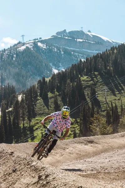 Downhill mountain biker ripping a dirt berm above Jackson Hole Mountain Resort